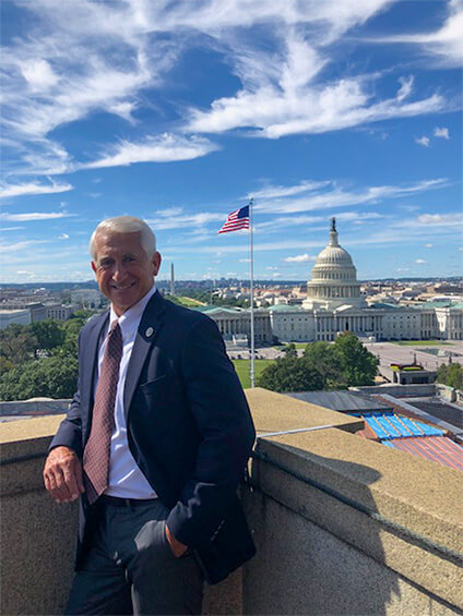 Dave Reichert posing on a balcony with the Capitol building in the background